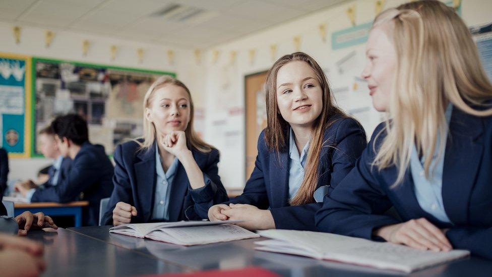 Teenagers chat in a classroom