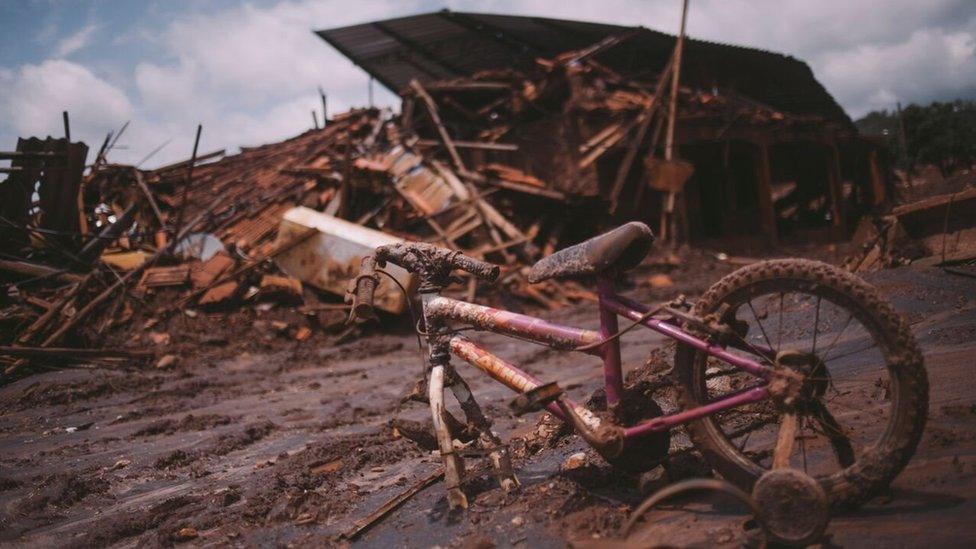 A child's bicycle got stuck in the mud next to the rubble of a house torn by the brown wave