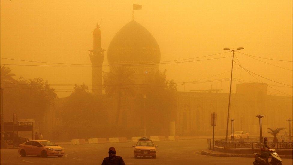 Cars and a motorbike in sandstorm, Baghdad, Iraq.