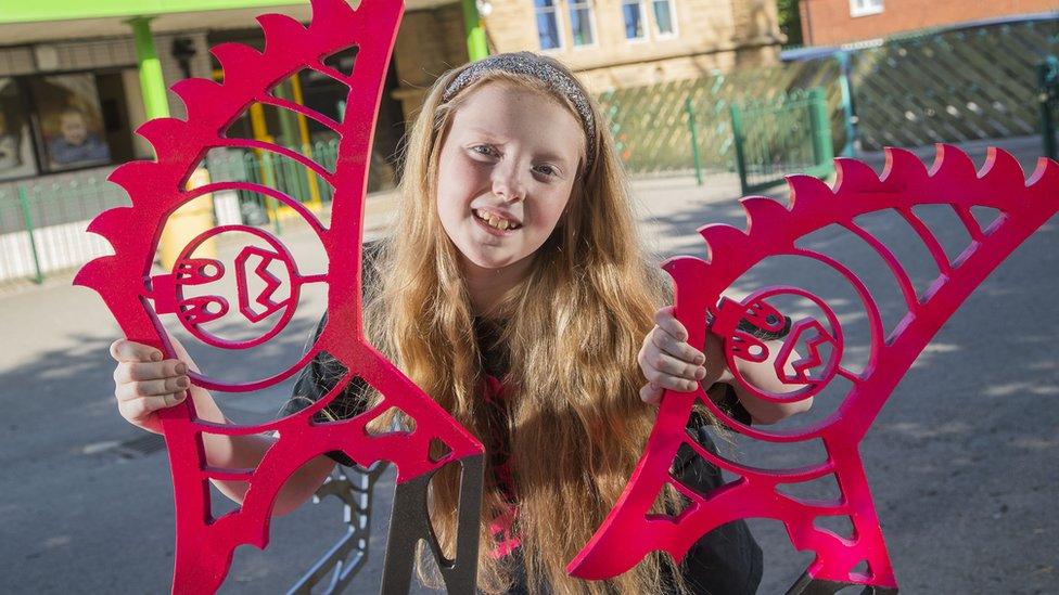 Schoolgirl April Prince holding up parts of the robot she designed and built.