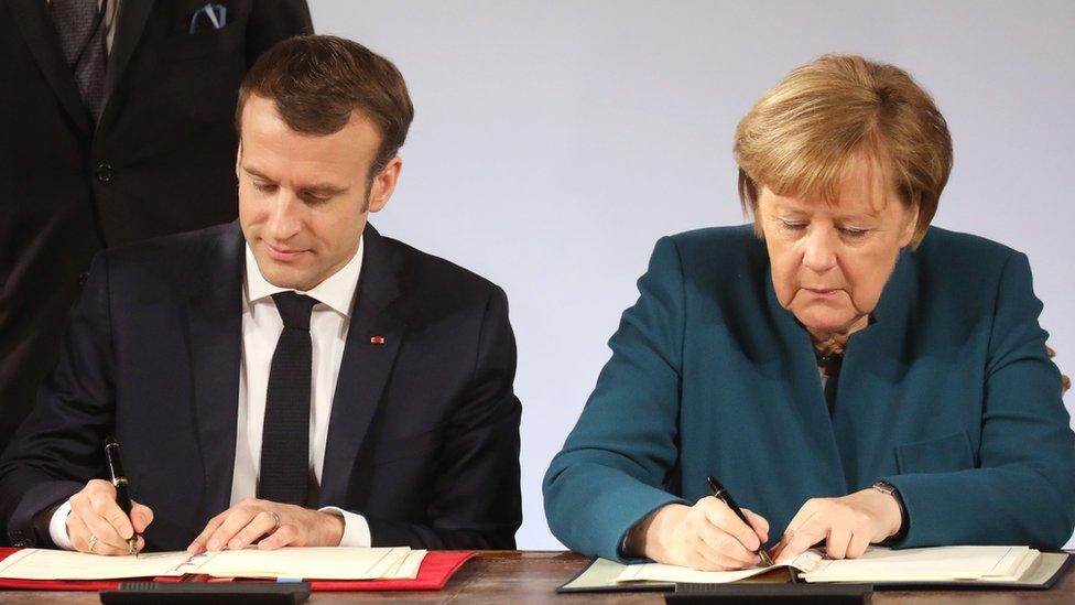 Mr Macron and Mrs Merkel sign the paper copies of the treaty