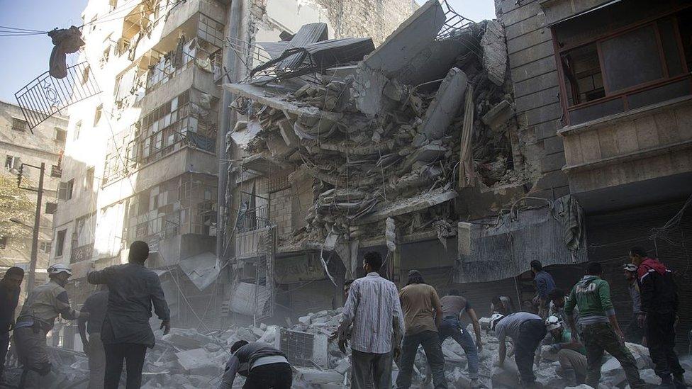 Syrian civilians and rescuers gather at site of government forces air strikes in the rebel held neighbourhood of Al-Shaar in Aleppo on September 27 2016