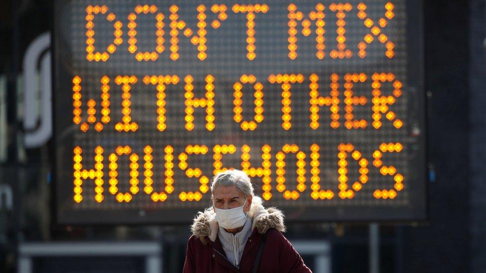 Woman in front of sign, which reads "Don't mix with other households"