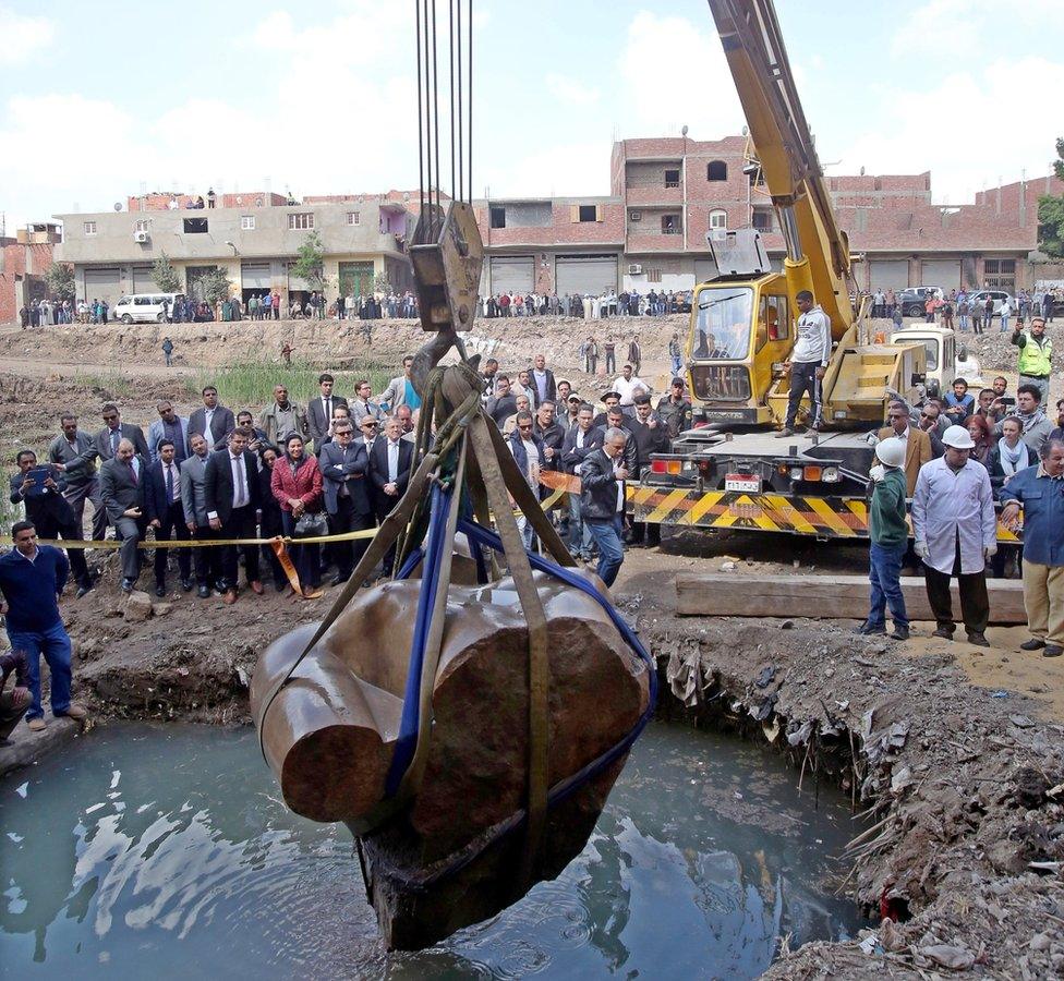 Egyptians look on as a crane lifts parts of a statue for restoration after it was unearthed at Souq al-Khamis district, at al-Matareya area, Cairo, Egypt, 13 March 2017