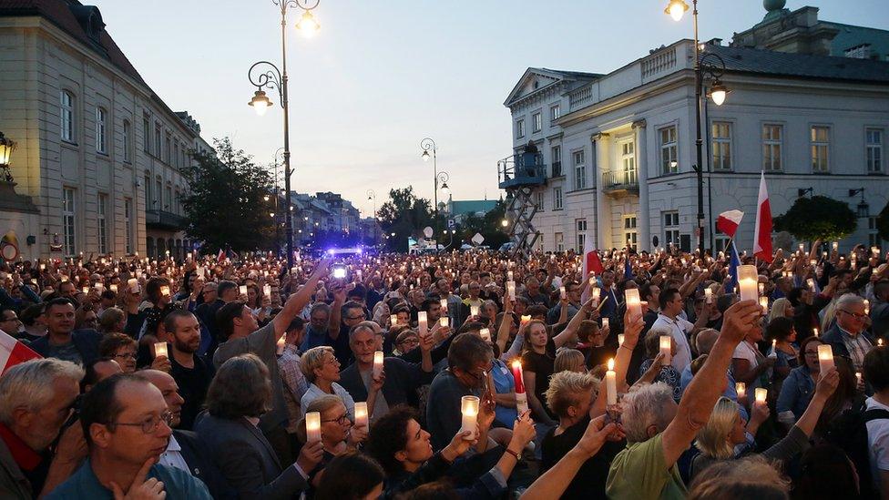 Protesters hold candles in front of the Presidential Palace in Warsaw, Poland, 18 July 2017