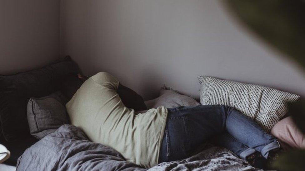 Stock image of a woman curled up distressed in bed