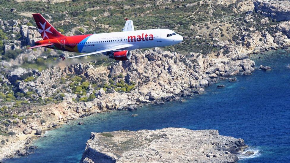 Air Malta passenger jet flying over coastline