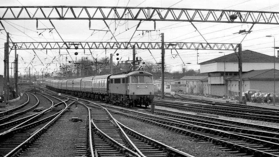 Train on track beneath electricity gantries