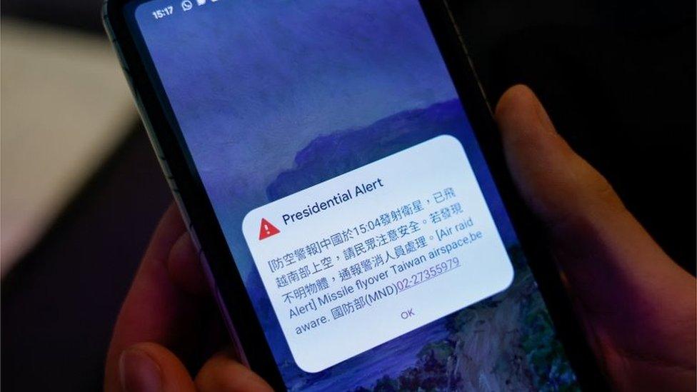 A person attending a Foreign Ministry"s news conference holds a phone showing air raid alert about a Chinese satellite that had flown over south Taiwan airspace in Taipei, Taiwan January 9, 2024.