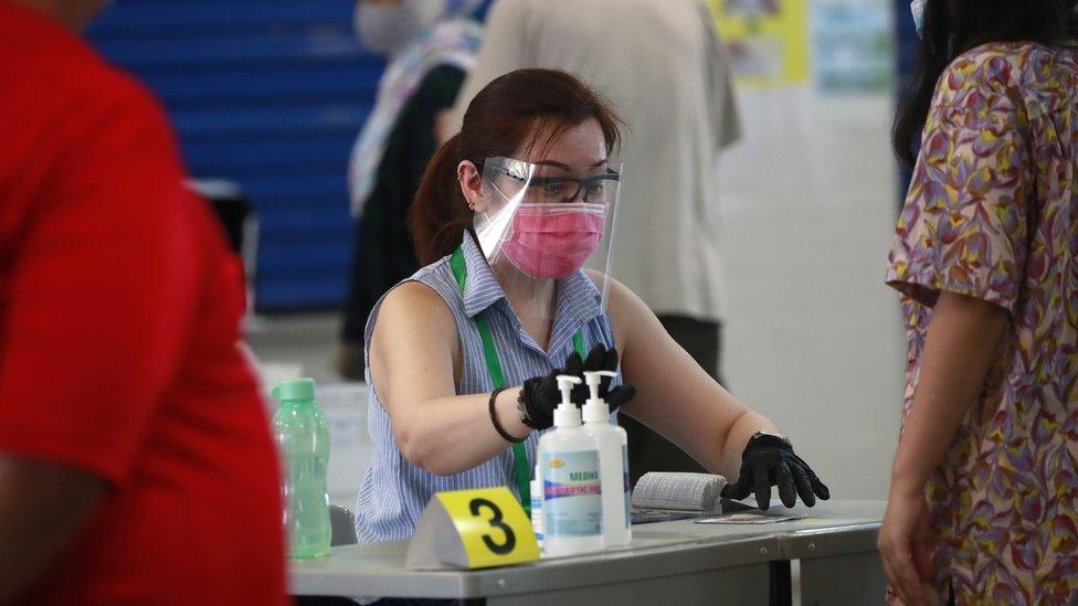 An official checks a voter's papers at a polling station in Singapore, 10 July 2020