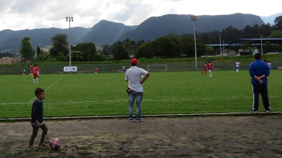 A child plays with a ball on the sidelines