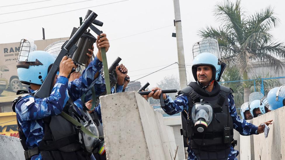 Police officers next to barricades erected on a national highway to stop farmers, who are marching towards New Delhi to press for the better crop prices promised to them in 2021, at the Singhu border in New Delhi, India, on 13 February 2024