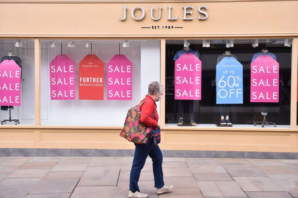 Person walks past Joules shop displaying sale