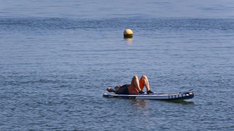 A man enjoys the warm weather on the beach in Whitstable, Kent,