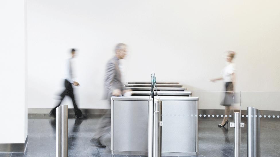 People entering their office via turnstile