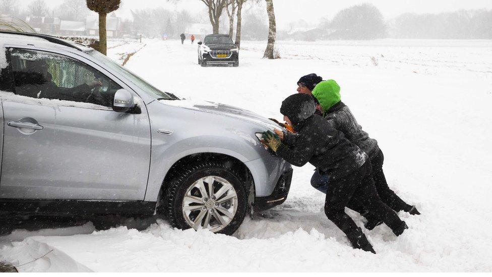 People push out a car that got stuck in a snow dune in Haarle, the Netherlands