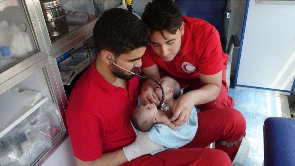 Red Crescent workers examine the babies