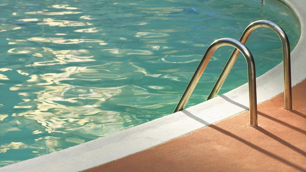 still of an empty swimming pool with a metal entry ladder