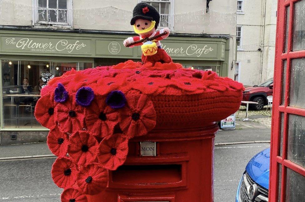 Knitted poppies and figure on a postbox topper in Ashbourne