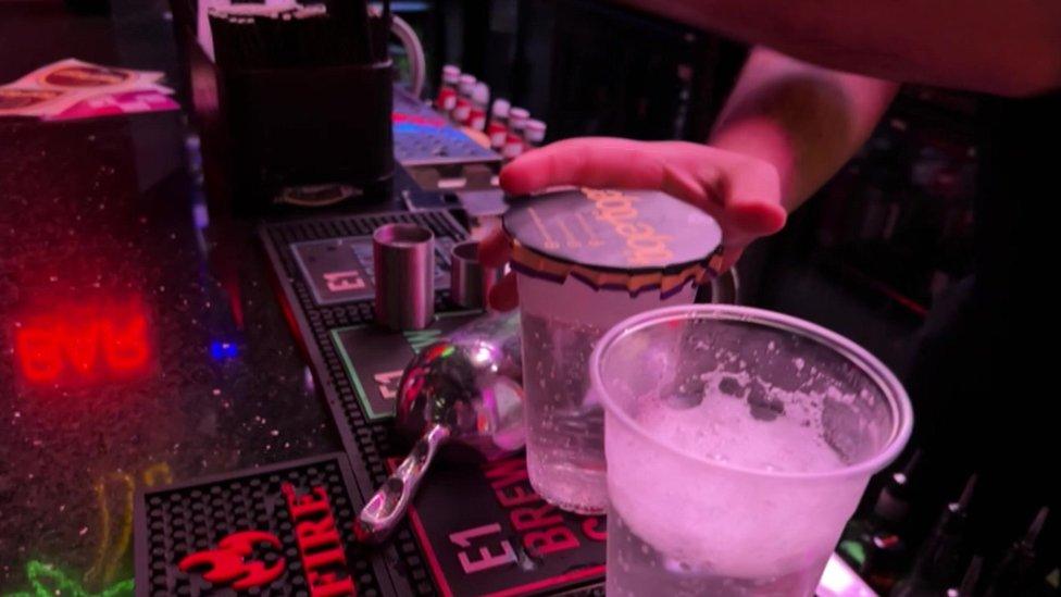 A member of bar staff at Tiger Tiger puts a paper cover on a drink before serving it