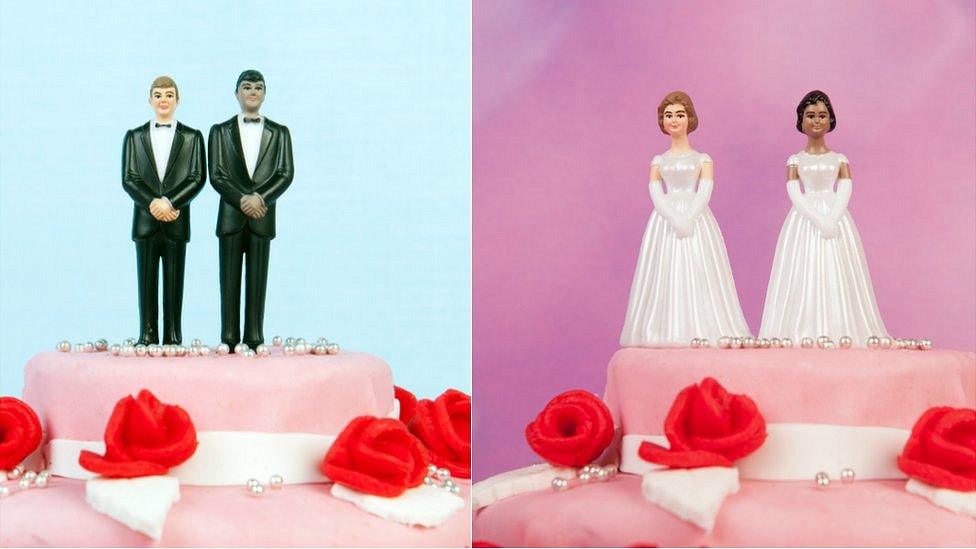 Two wedding cakes, one topped by two men in suits and the other by two women in wedding dresses