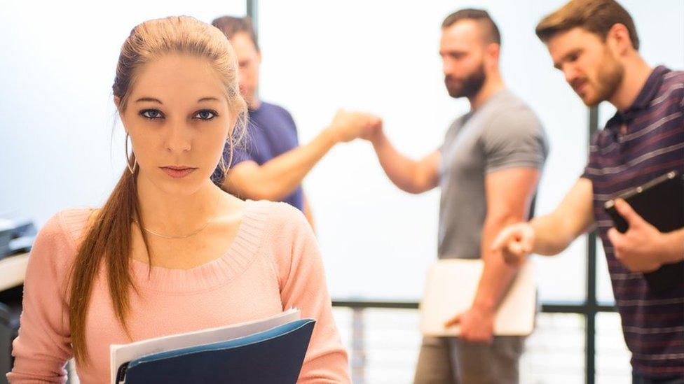 Men pointing at woman as she walks away