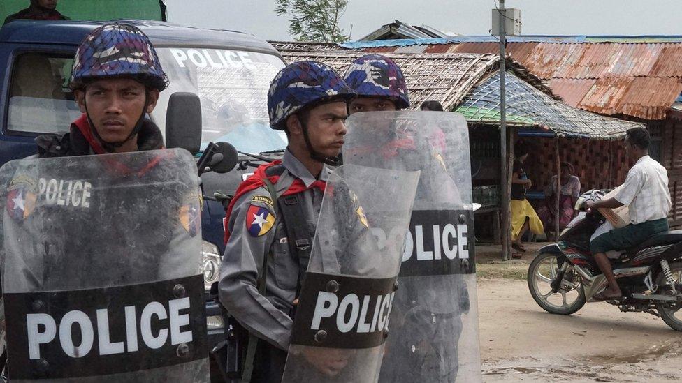 three police officers with helmets and shields looking wary