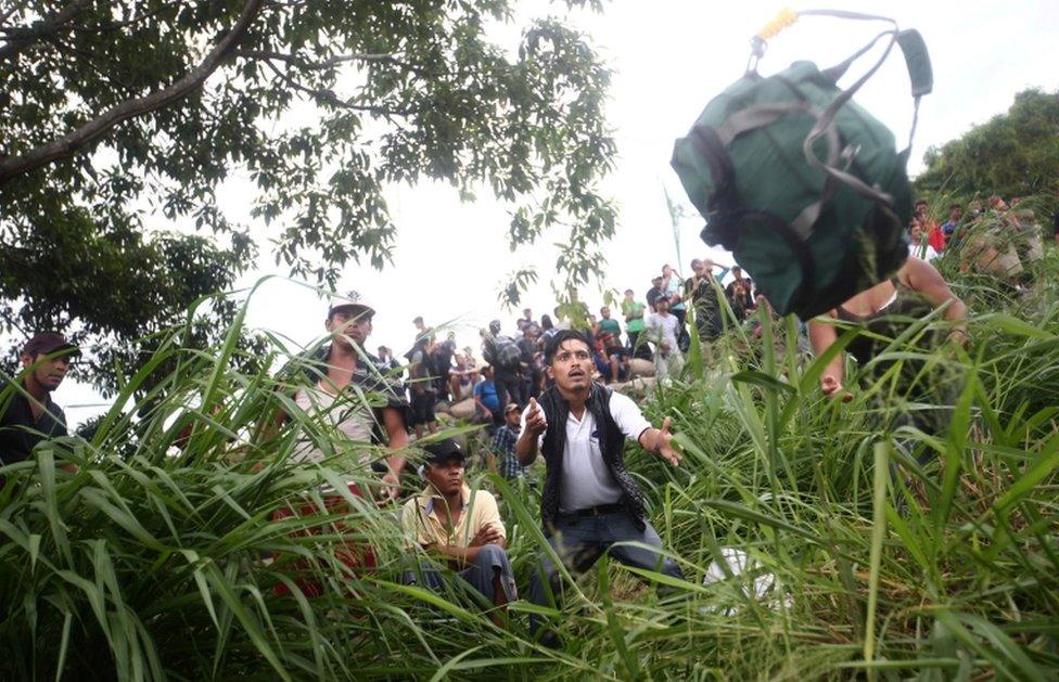 A Honduran man catches a backpack thrown to him after crossing the Suchiate river