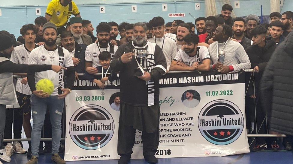 Hashim's father handing the trophy to the winners