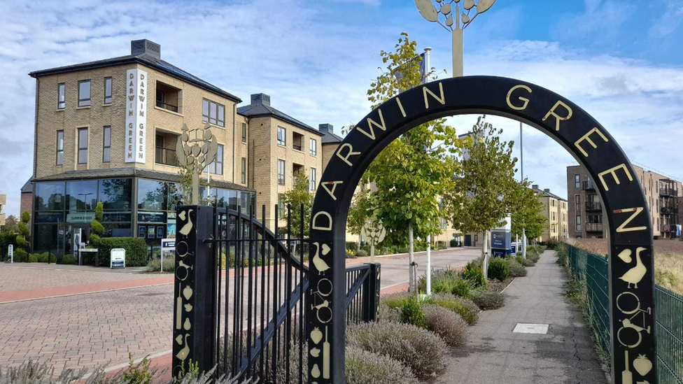 Arched gate with Darwin Green written over and buildings in the background