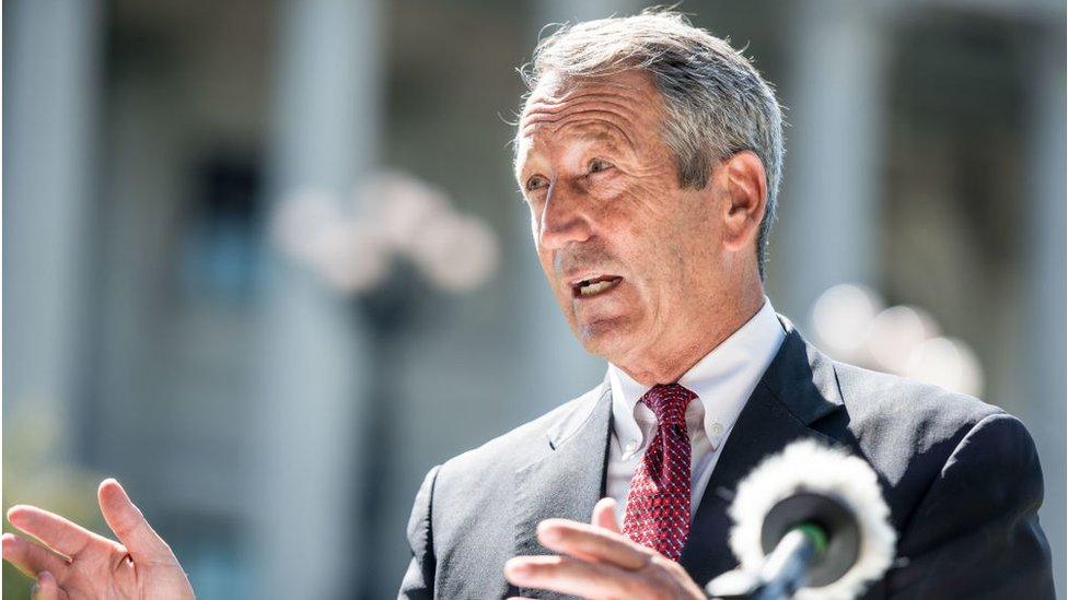 Former South Carolina Gov Mark Sanford speaks to the media with a cardboard cutout of President Donald Trump during a campaign stop at the state house in September