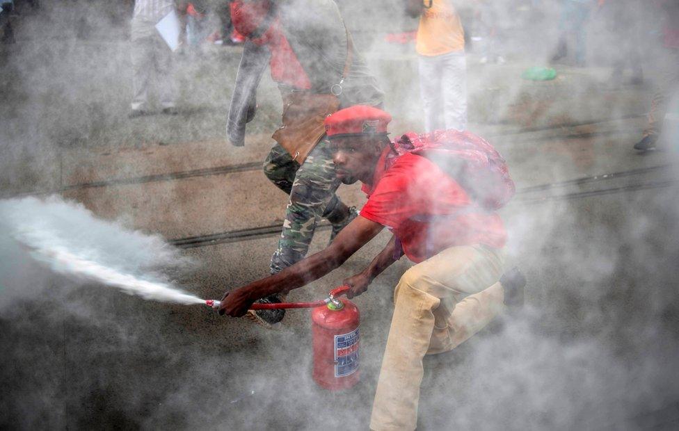 An EFF supporter sprays a fire extinguisher as members and supporters of the South African opposition party, the Economic Freedom Fighters (EFF), demonstrate against South Africa"s president Jacob Zuma