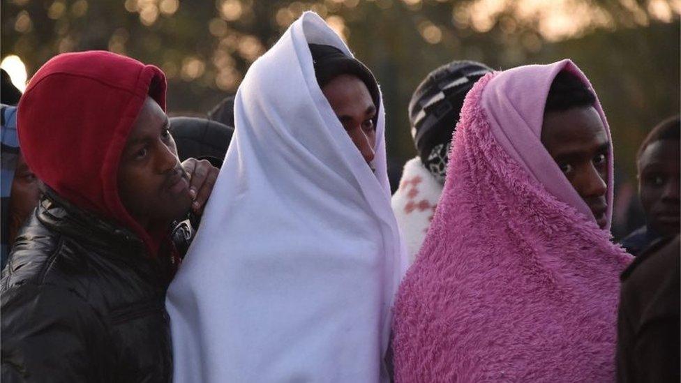 Migrants queue outside an aid station, to be assigned to one of the processing centres across France, near the "Jungle" migrant camp in Calais, northern France, on 27 October 2016