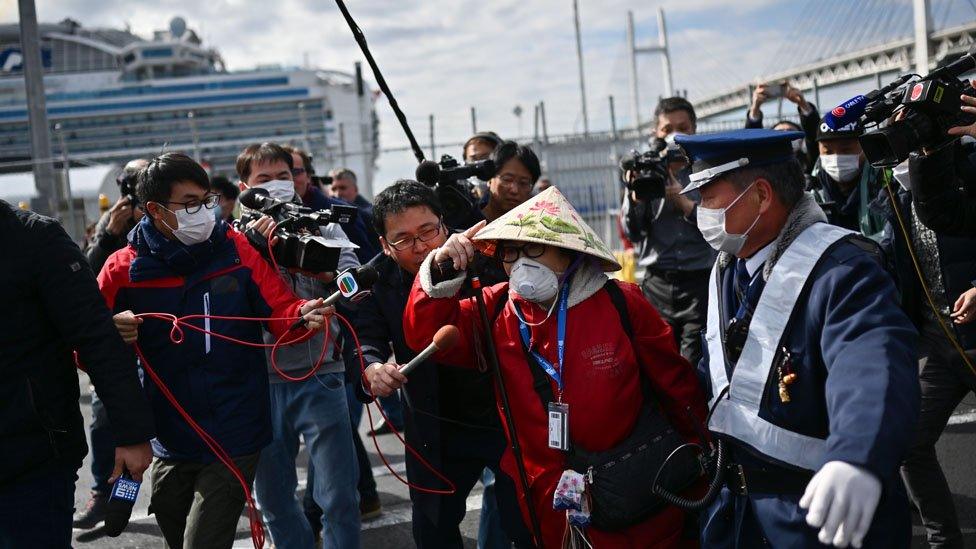 A passenger (centre R) leaves on foot after disembarking the Diamond Princess cruise ship in quarantine due to fears of the new COVID-19 coronavirus, at the Daikoku Pier Cruise Terminal in Yokohama on February 19, 2020.