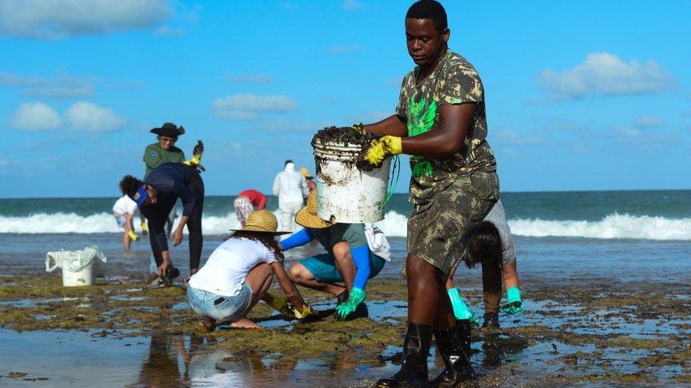 A man works to remove an oil spill on Muro Alto beach in Tamandare, Pernambuco