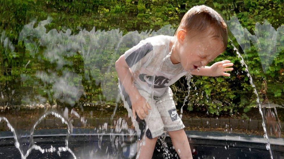 A little boy laying in a fountain