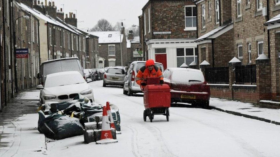 A postman makes deliveries through the snow in York