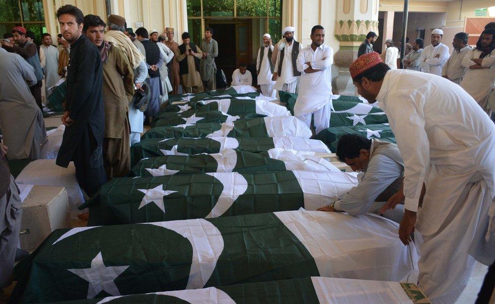 Pakistani mourners gather around the coffins, draped in Pakistan flags, of some of those killed in the attack, Quetta, 25 October 2016.