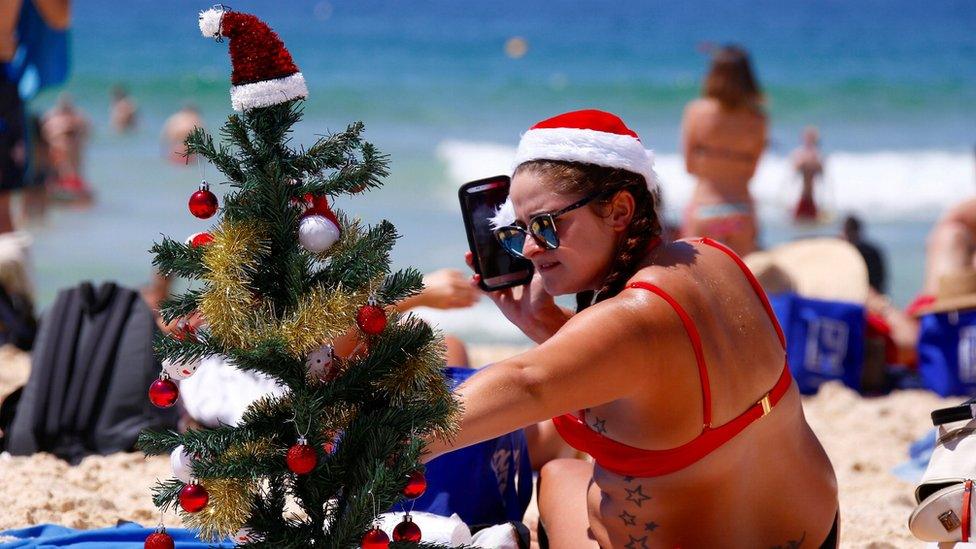 Irish backpacker Genna Woods adjusts her small Christmas tree she planted in the sand as she celebrates Christmas Day at Sydney's Bondi Beach in Australia, 25 December, 2016