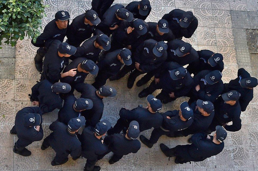 Algerian anti-riot police are seen from above, huddling in a group.