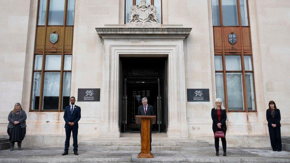 Y Prif Weinidog, Mark Drakeford, gydag aelodau eraill o'r cabinet a swyddogion yn nodi'r cofio cenedlaethol o flaen swyddfa'r Llywodraeth ym Mharc Cathays, Caerdydd