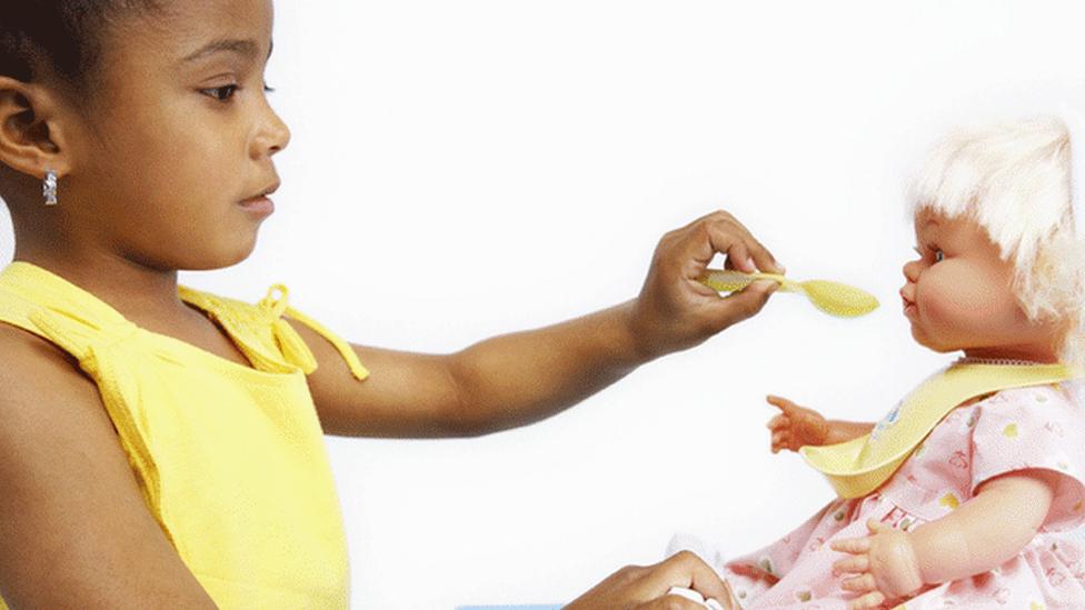 Girl feeding a doll