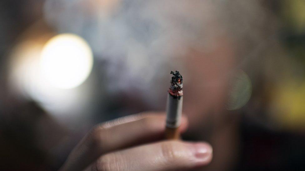 Cigarette being held and smoke obscuring a man's face