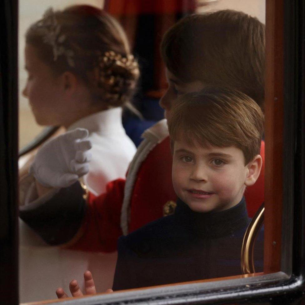 Prince Louis with his brother Prince George and sister Princess Charlotte waving from a carriage as they leave the Coronation