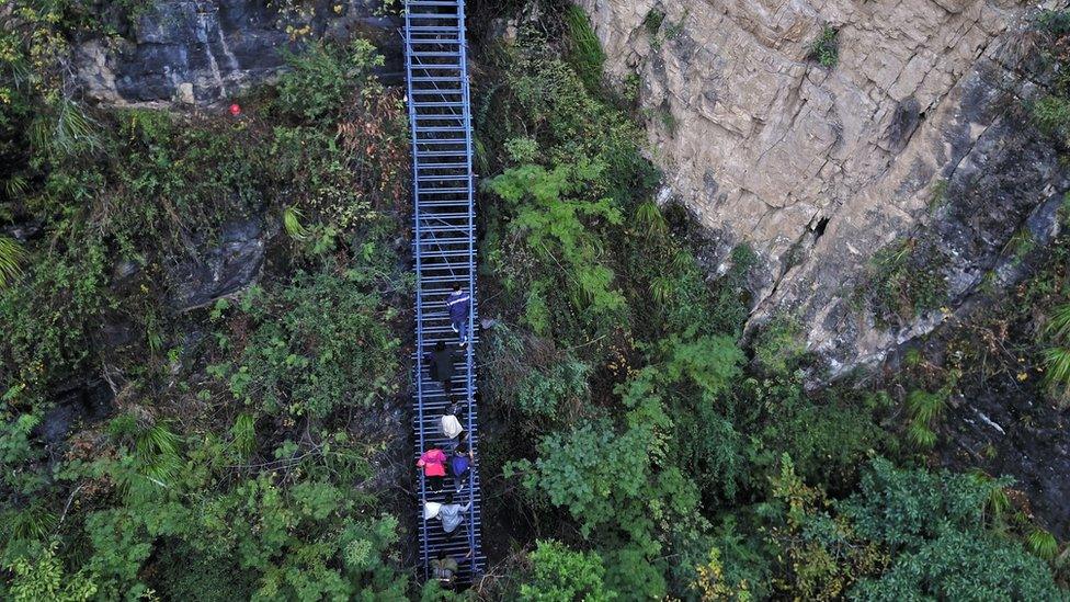 People climb on the newly-built metal ladder with hand railings to Atuler village on a cliff on November 11, 2016 in Zhaojue county, China.