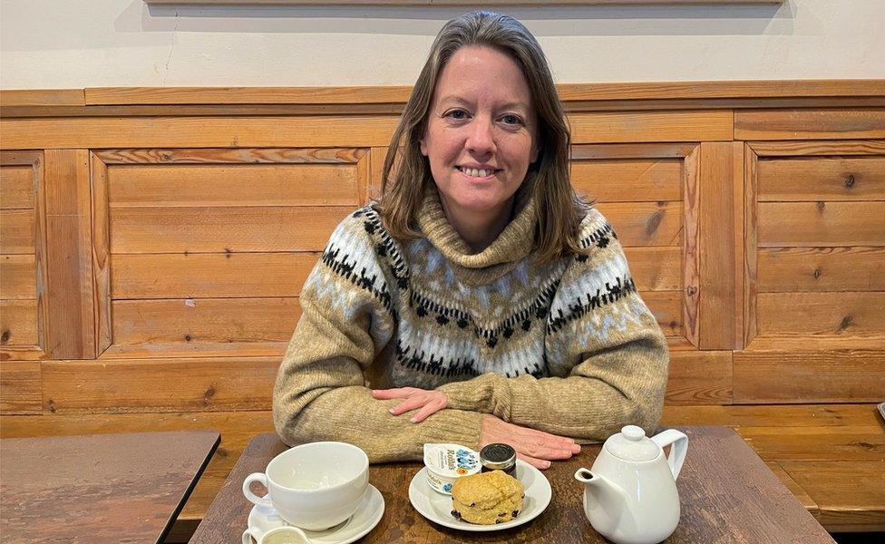 Sarah Merker sits in a National Trust cafe with a scone and pot of tea