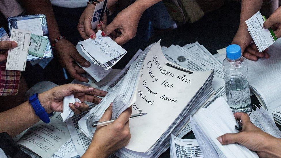 People handing over names and IDs at a Manila polling station, to receive their ballots