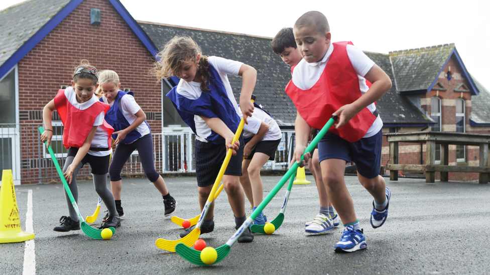 School children play hockey outdoors