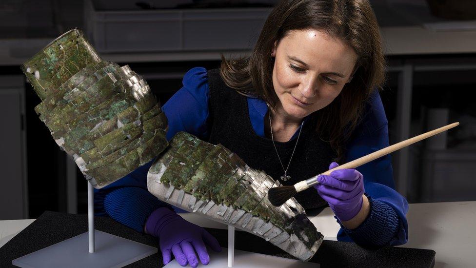 bethan bryan carefully brushes a section of the reconstructed armour