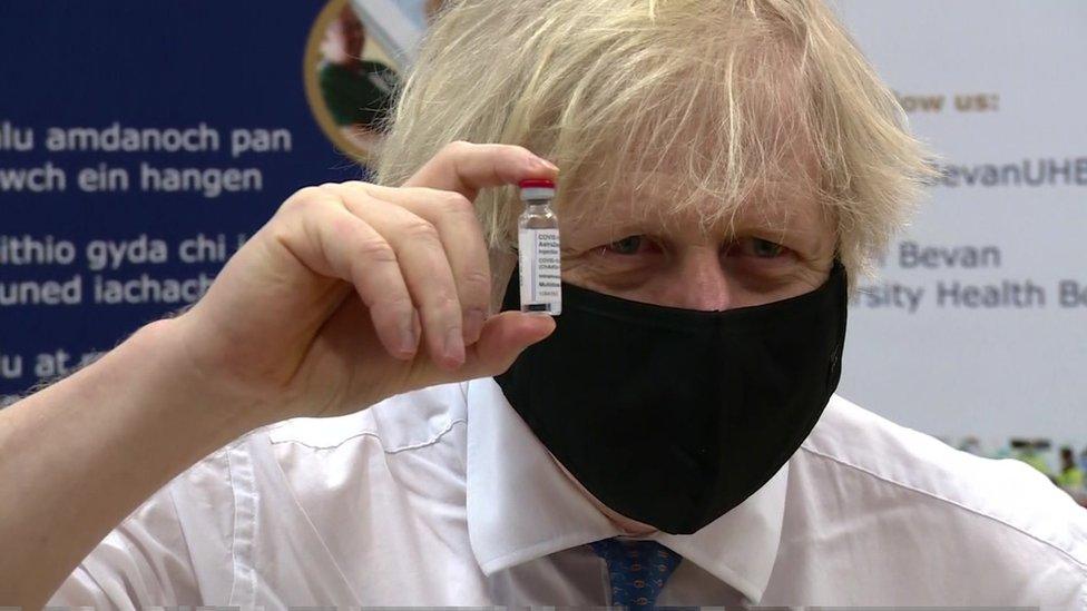 Boris Johnson holds up a vaccine vial